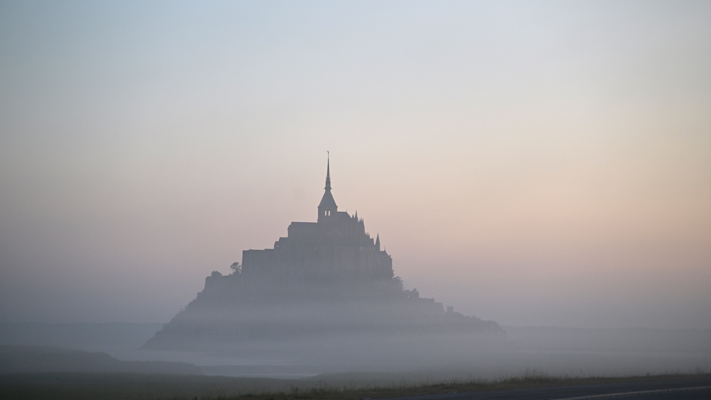 Cette photographie montre le Mont-Saint-Michel dans le nord-ouest de la France, enveloppé dans la brume tôt le matin, le 9 juillet 2025. (Photo de Damien Meyer / AFP)