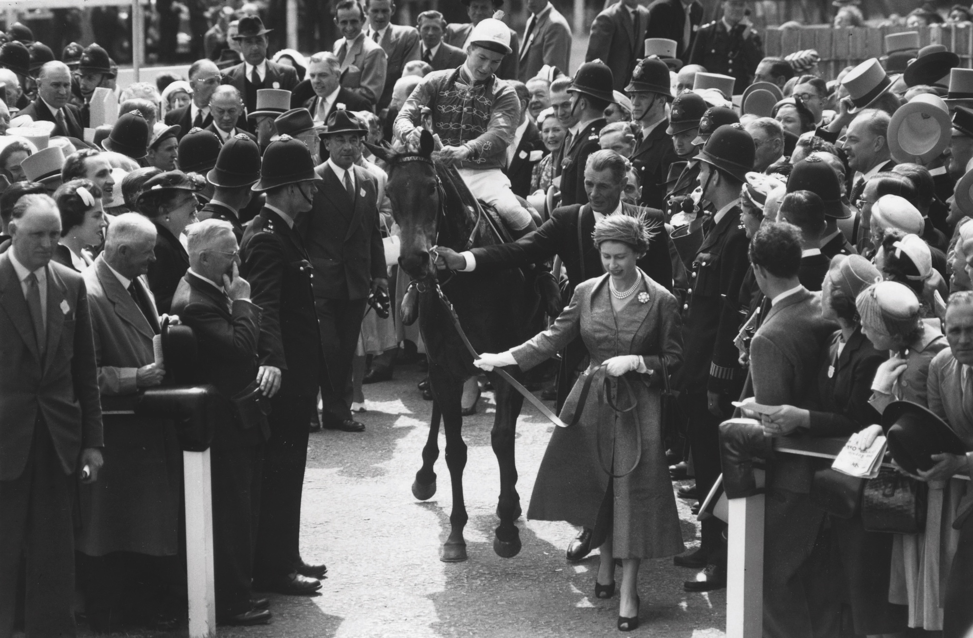 7 juin 1957 : la reine Elizabeth II de Grande-Bretagne mène son cheval « Carrozza » et son jockey Lester Piggott dans l'enceinte du vainqueur à l'hippodrome d'Epsom, dans le Surrey.
