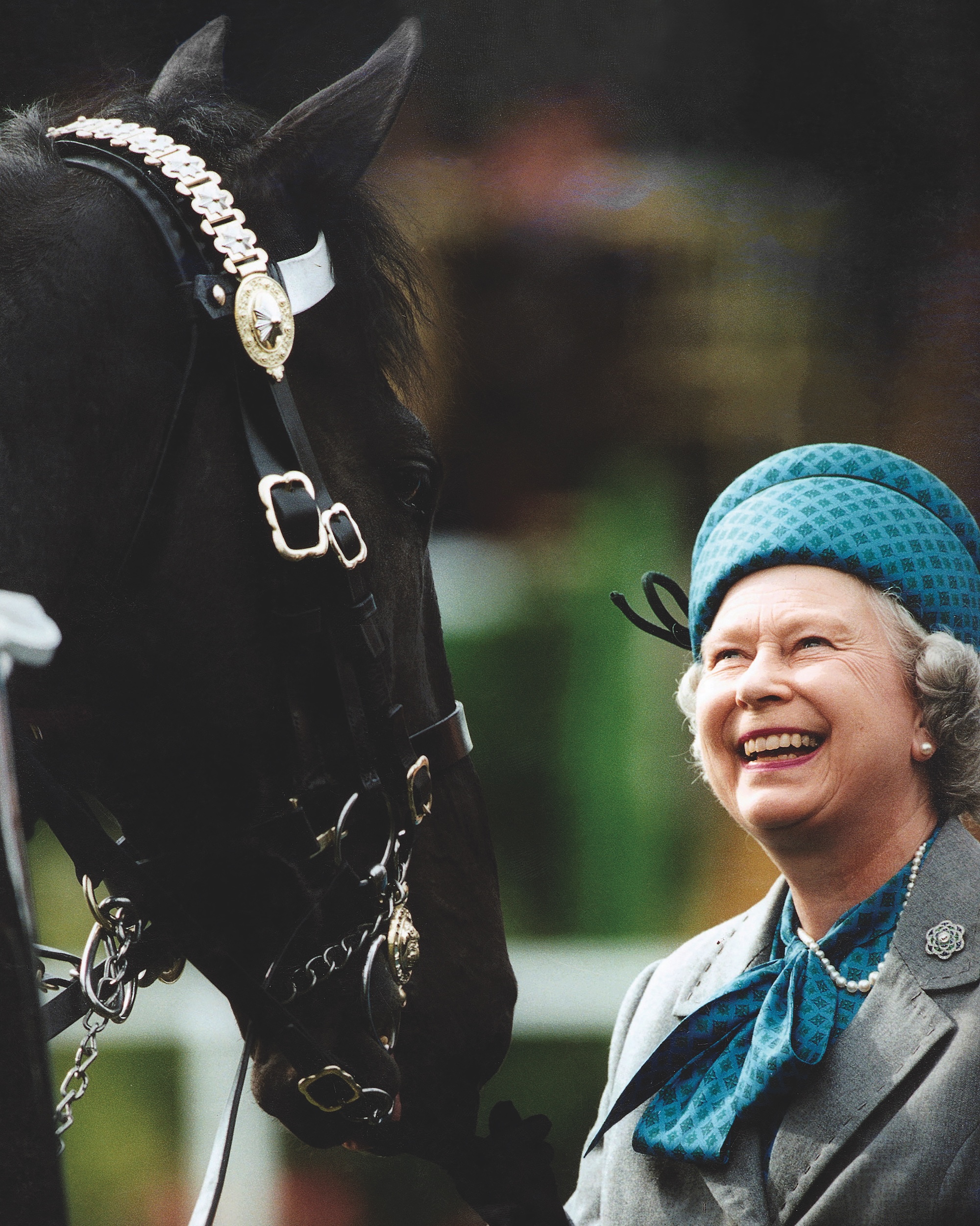 La reine Elizabeth II sourit alors qu'elle passe en revue les troupes montées sur des chevaux au Royal Windsor Horse Show.