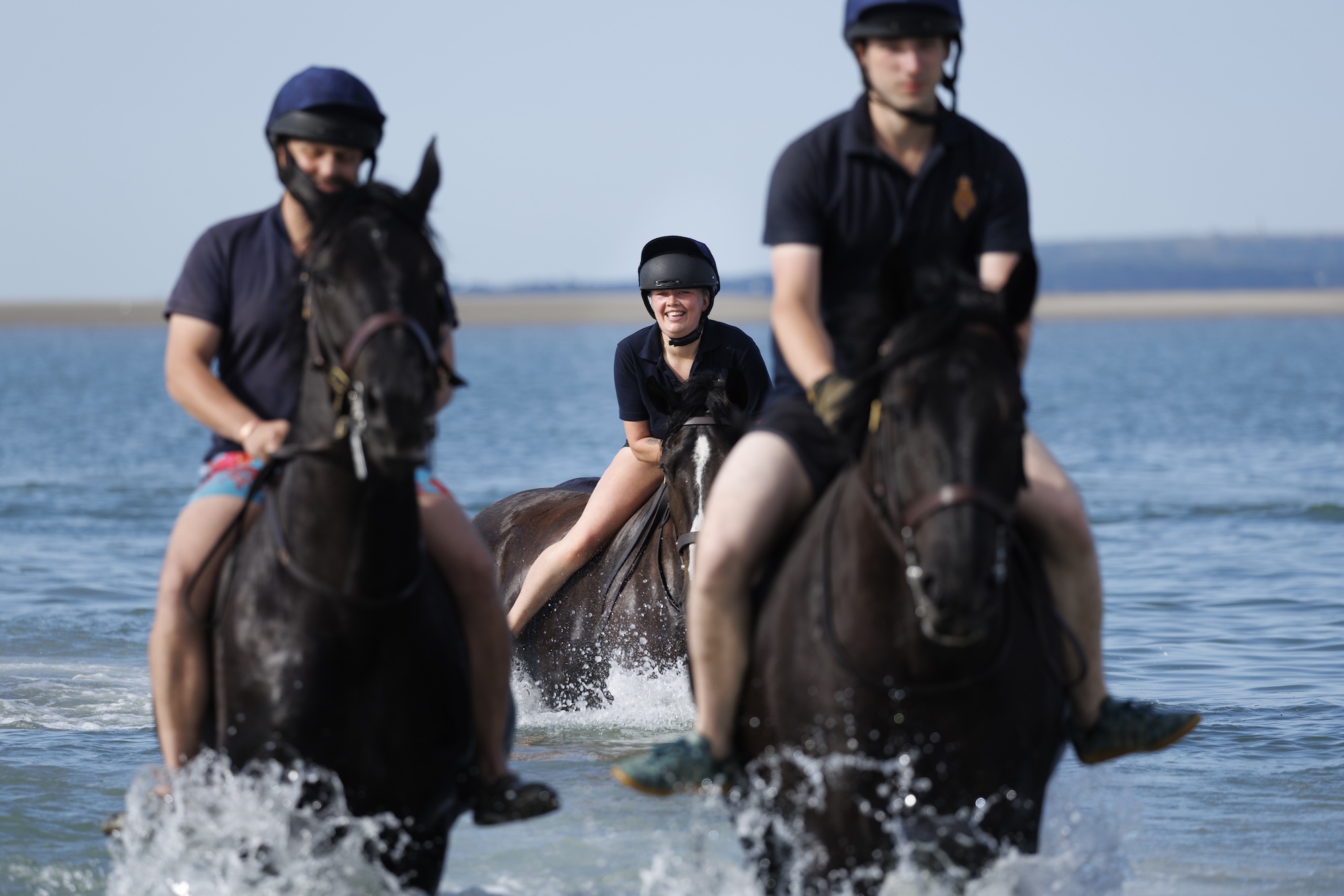 Sur la photo : des soldats et des chevaux du Household Cavalry Mounted Regiment à la plage de Hayling Island le vendredi 3 juillet 2026. Le Household Cavalry Mounted Regiment troque les rues de Londres pour les rives du Hampshire. Dans le cadre de leur camp d'été de trois semaines, les Life Guards et les Blues and Royals ont déployé leurs chevaux de travail militaires à Hayling Island Beach pour une journée d'entraînement équin différent. Après avoir accueilli quatre dirigeants mondiaux à Windsor, protégé le roi lors de l'ouverture officielle du Parlement et organisé un spectaculaire défilé pour l'anniversaire du roi, une journée à la mer semblait bien méritée. Ces chevaux sont confrontés chaque jour au bruit et au chaos de Londres – aux sirènes, à la foule et à tous les plaisirs inattendus de la vie urbaine. Il est donc essentiel de renforcer leur confiance en eux en les exposant à de nouveaux environnements. La plage – avec ses sables mouvants, ses vagues déferlantes, ses mouettes hurlantes et ses enfants surexcités – est le terrain d’essai idéal. Pour les plus jeunes chevaux, c'était leur toute première rencontre avec la mer. Regarder